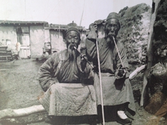 Black and white photo of locals smoking long pipes; Bezeklik Thousand Buddha Cave complex