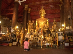 Praying to the gold Buddha inside Wat Mai Suwannaphumaham; Luang Prabang