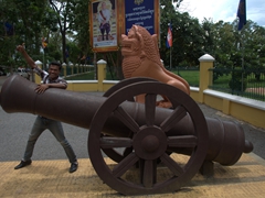 One of our friendly tour guides strikes a pose next to a canon outside the Governor's Palace; Battambang