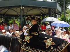 A young girl in an elaborate costume smiles and poses prettily during the Pase del Niño Viajero