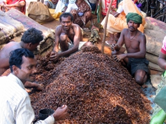 Locals gather around a huge pile of sticky bean pods (used for alcohol and cooking)