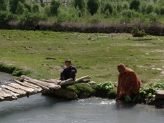 Robby asks and receives permission to take this photo of a lady washing vegetables in the river with her son hanging out nearby