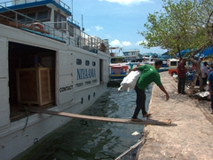 Wooden planks are erected from fishing boat to fishing boat and eventually to the harbor as workers transport goods to and from their vessels; Male