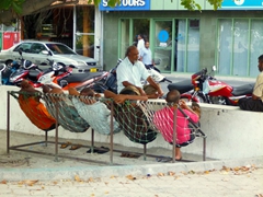Locals sitting in makeshift chairs gossiping the afternoon away; Male