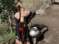 Detail of a Kalasha woman drawing water from the well