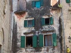 Green window shutters in a pyramid formation make this unique building stand out in medieval Kotor