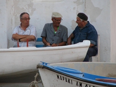Three elderly Greek men engaged in conversation as the sun sets over another beautiful day