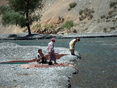 Tajik women washing blankets in the freezing cold glacial waters; base of Fann Mountain range
