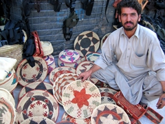 A vendor with the most amazing blue eyes showing off his wares for sale; Kabul bazaar