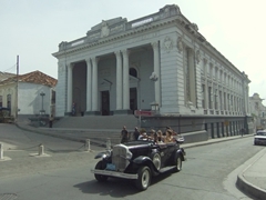 A vintage taxi passes in front of the Emilio Bacardi Museum