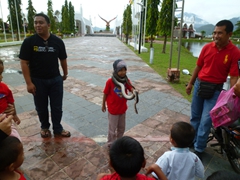 A fearless Malaysian girl shows the boys how its done by wrapping a snake around her neck while the horrified boys look on; Langkawi