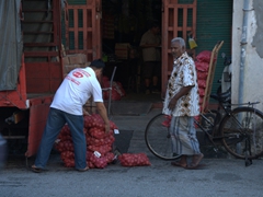 A worker stacks onions onto the back of a truck; Penang