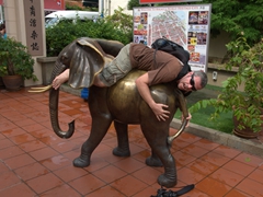 Robby mounts an elephant in a small park off Jonker Street
