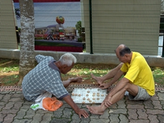 Two old friends play an impromptu street session of some kind of strategy game; Malacca
