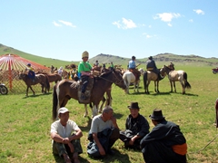 Mongolian men huddled in gossip at the conclusion of a regional Naadam Festival