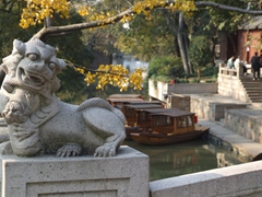 A lion statue bridge marker with Tiger Hill's canal system in the background