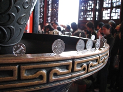 Visitors to the temple carefully balance upright coins along the rim of this bowl
