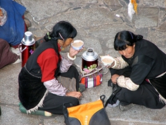 Two women share a thermos of hot tea