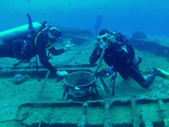 Robby points to David trying on a gas mask left behind on the troop carrier; Coolidge dive wreck