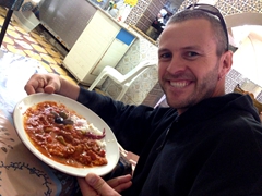 Robby enjoying lunch of merguez (spicy lamb or goat sausages) doused with harissa