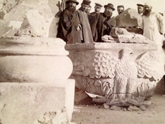 Old photo of visitors surrounding a carved eagle capitol at Zvartnots