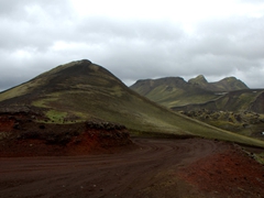 Red road cutting through green hills leading down to Landmannalaugar
