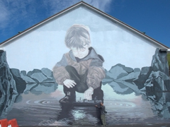 Robby is dwarfted by a massive mural painted on a harbor building; Heimaey Island