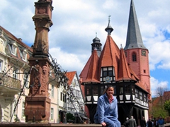 Becky strikes a pose at Michelstadt's main market square with the town's four landmarks visible (the city fountain, the pink New Town Hall, the Pfarrkirche aka "reformed church" whose red brick steeple is in the background, and the half-timbered Old Town Hall